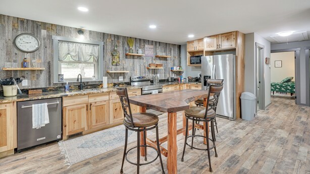 Une cuisine moderne avec des meubles en bois, un réfrigérateur en acier inoxydable et un grand îlot central doté de tabourets de bar.