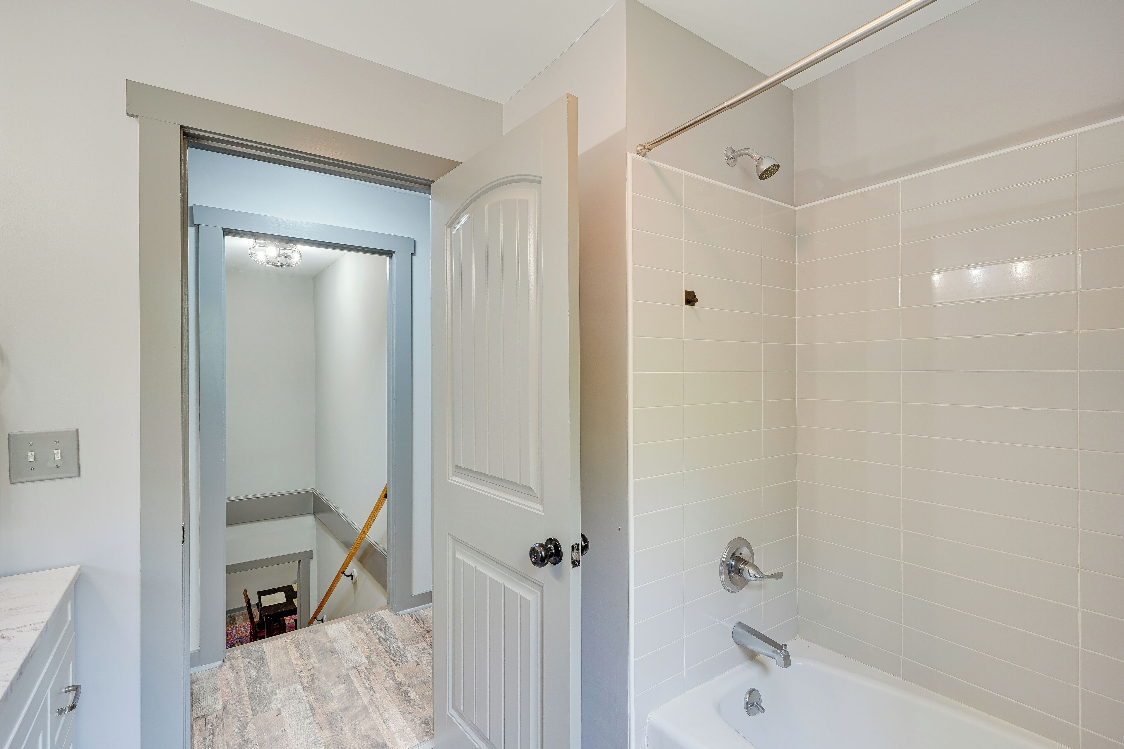A bathroom with a bathtub, a shower, and a door leading to a hallway.