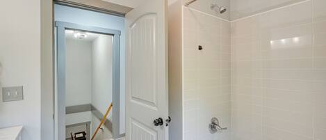 A bathroom with a bathtub, a shower, and a door leading to a hallway.