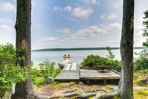 Relax on the lakeside dock with a bench and table, surrounded by lush greenery and a serene lake view.