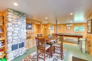 Un interior de madera con una pared de piedra, una mesa de billar y un comedor.