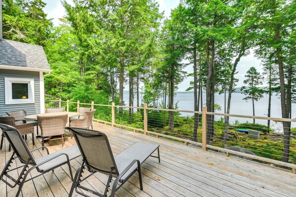 Relax on the deck with wicker chairs and a table, taking in the scenic views of the surrounding water and trees.