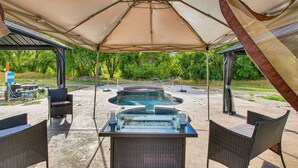An outdoor patio with a hot tub, wicker chairs, and a covered area with a canopy. - Preston Summer Getaway: Sugar Creek Apartment (Preston)