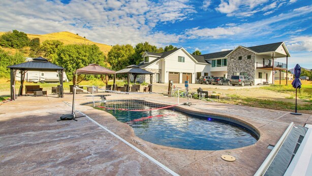 A swimming pool with a stone surround, a gazebo, and a house with a stone facade in the background. - Preston Summer Getaway: Sugar Creek Apartment (Preston)