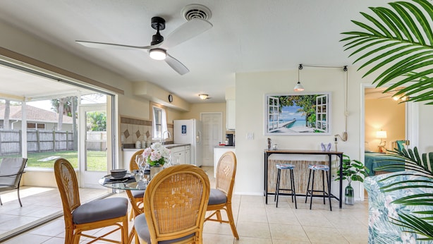 A spacious kitchen with a dining area, a ceiling fan, and a large window overlooking a backyard. - Venice Home w/ Fenced Yard: 4 Mi to Beach! (Venice)
