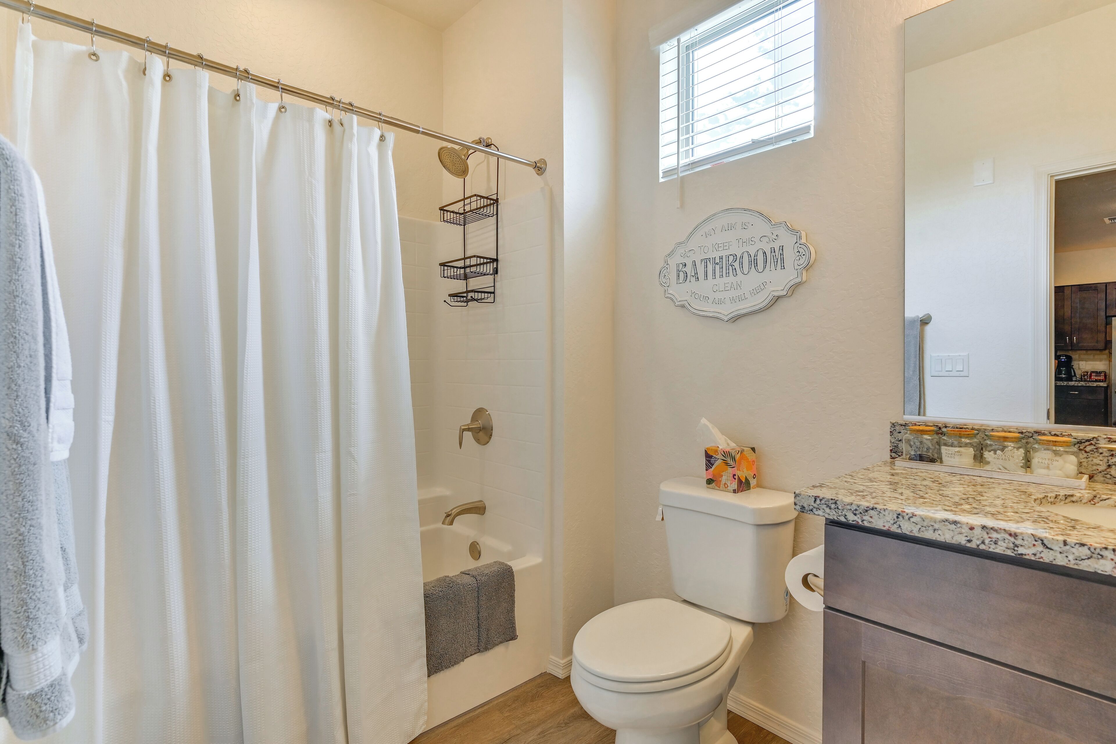 Un bagno con tenda doccia, vasca, water e mobile lavabo con specchio.