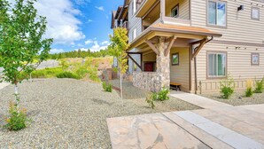 A multi-story building with a stone foundation, a gravel driveway, and a small tree.