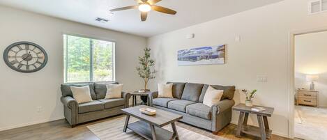 A spacious living room with a gray sofa, a coffee table, and a ceiling fan.