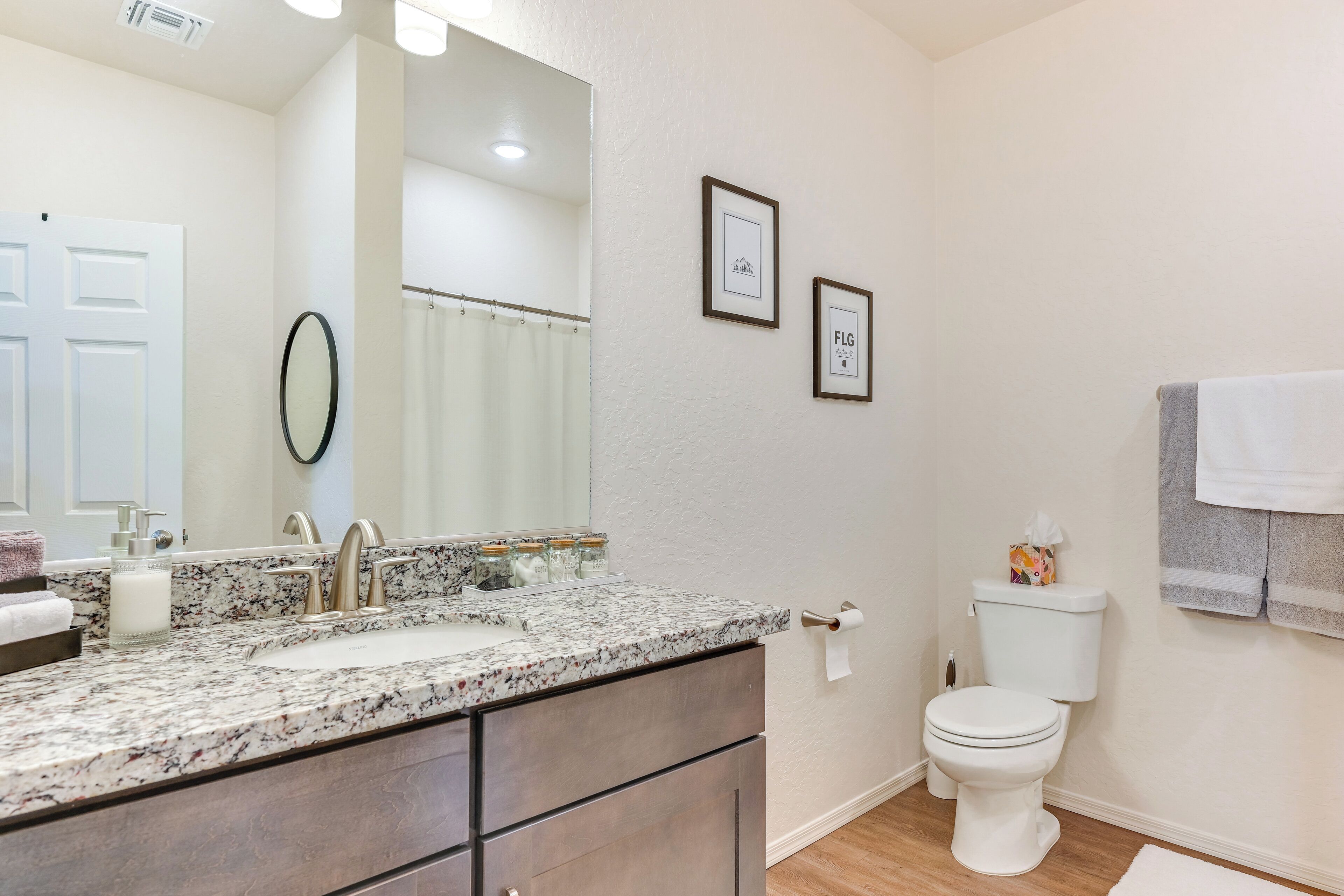 Ein Badezimmer mit Marmorwaschbecken, Toilette und gerahmten Bildern an der Wand.