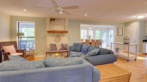 A spacious living room with a large sectional sofa, a ceiling fan, and a view into the adjacent dining area. - Lakefront Lineville Retreat w/ Private Dock! (Lineville)