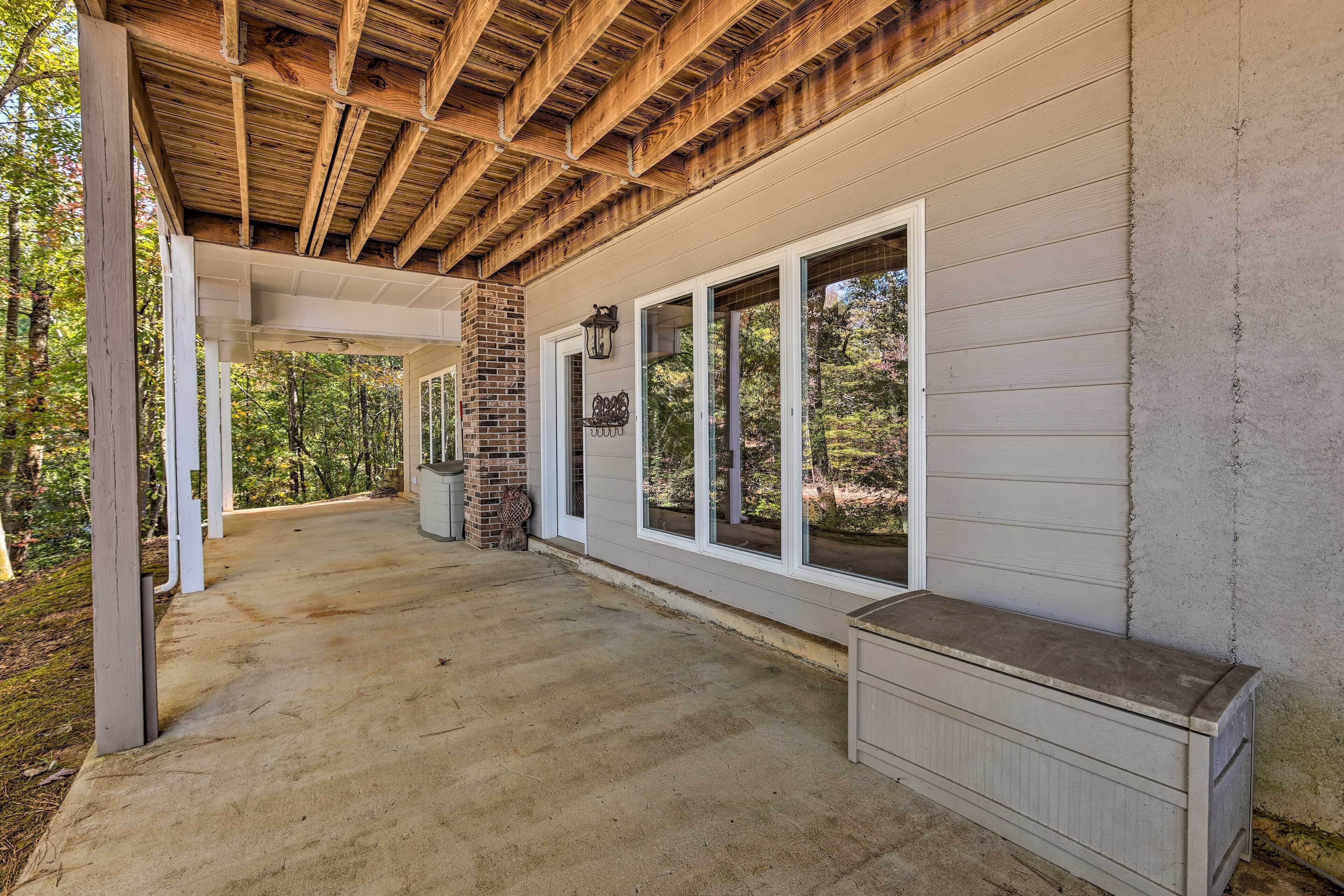 A covered porch with a concrete floor, white siding, and large windows.