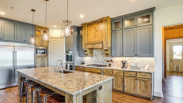 A kitchen with a large island, bar stools, and wooden cabinets. - Elegant 'sunset Meadow Ranch' in Texas w/ Hot Tub (Ponder)