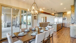 A spacious kitchen with a dining area, large windows, and a chandelier. - Elegant 'sunset Meadow Ranch' in Texas w/ Hot Tub (Ponder)