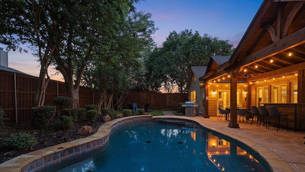 A swimming pool with a wooden deck and outdoor seating area.