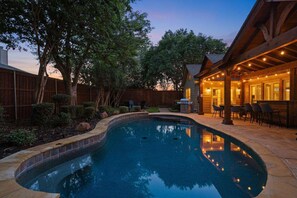 A swimming pool with a wooden deck and outdoor seating area. - 5BD,2BA w Backyard Oasis, Pool, Jacuzzi, Firepit (Corinth)