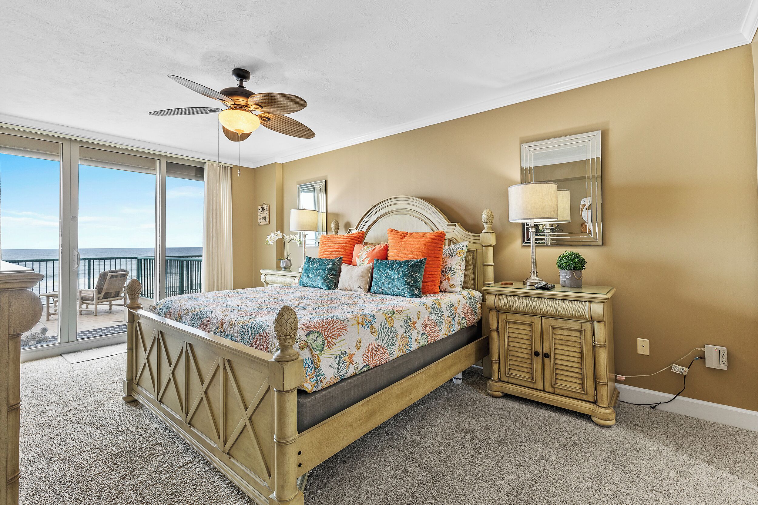 A bedroom with a bed, a nightstand, a dresser, a ceiling fan, and a view of the outdoors.