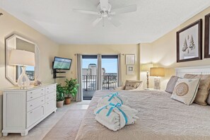 Un dormitorio con cama, cómoda, televisor y balcón con vistas.
