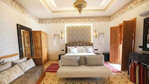 A spacious bedroom with a large bed, a sofa, and a wardrobe. - Riad Palais MERYEM (Marrakech)