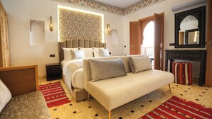 A bedroom with a bed, a sofa, a patterned wall, a mirror, and a decorative rug. - Riad Palais MERYEM (Marrakech)