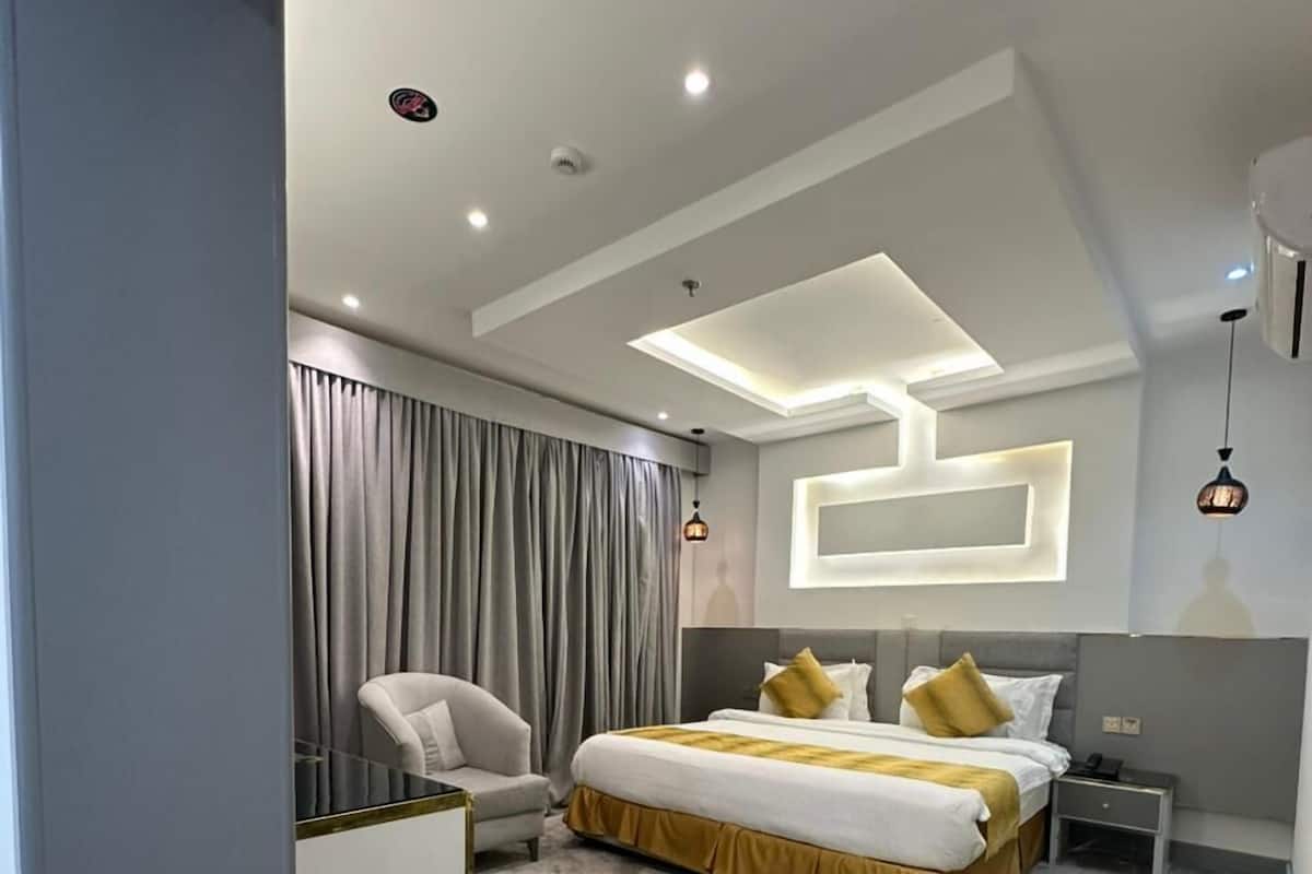 A modern hotel room with a large bed, a seating area, and a small table.