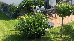 A house with a tiled roof, a patio with a table and chairs, and a small garden area.