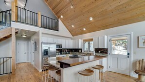 Una cocina amplia con una isla grande, piso de madera y techo alto con vigas a la vista.
