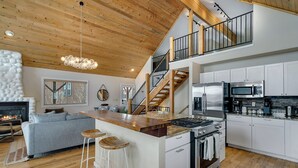 Una cocina moderna con una isla central, armarios blancos y electrodomésticos de acero inoxidable.