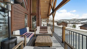 Una terraza de madera con un sofá, una mesa y una chimenea.
