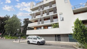 A modern multi-story building with balconies, a car parked in front, and a clear sky. - Apart-Chic-Les-Ulis with terrace and parking. (Les Ulis)