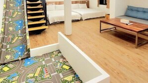 A modern interior with a staircase, two beds, a sofa, and a wooden coffee table. - Happiness YES (Yilan)