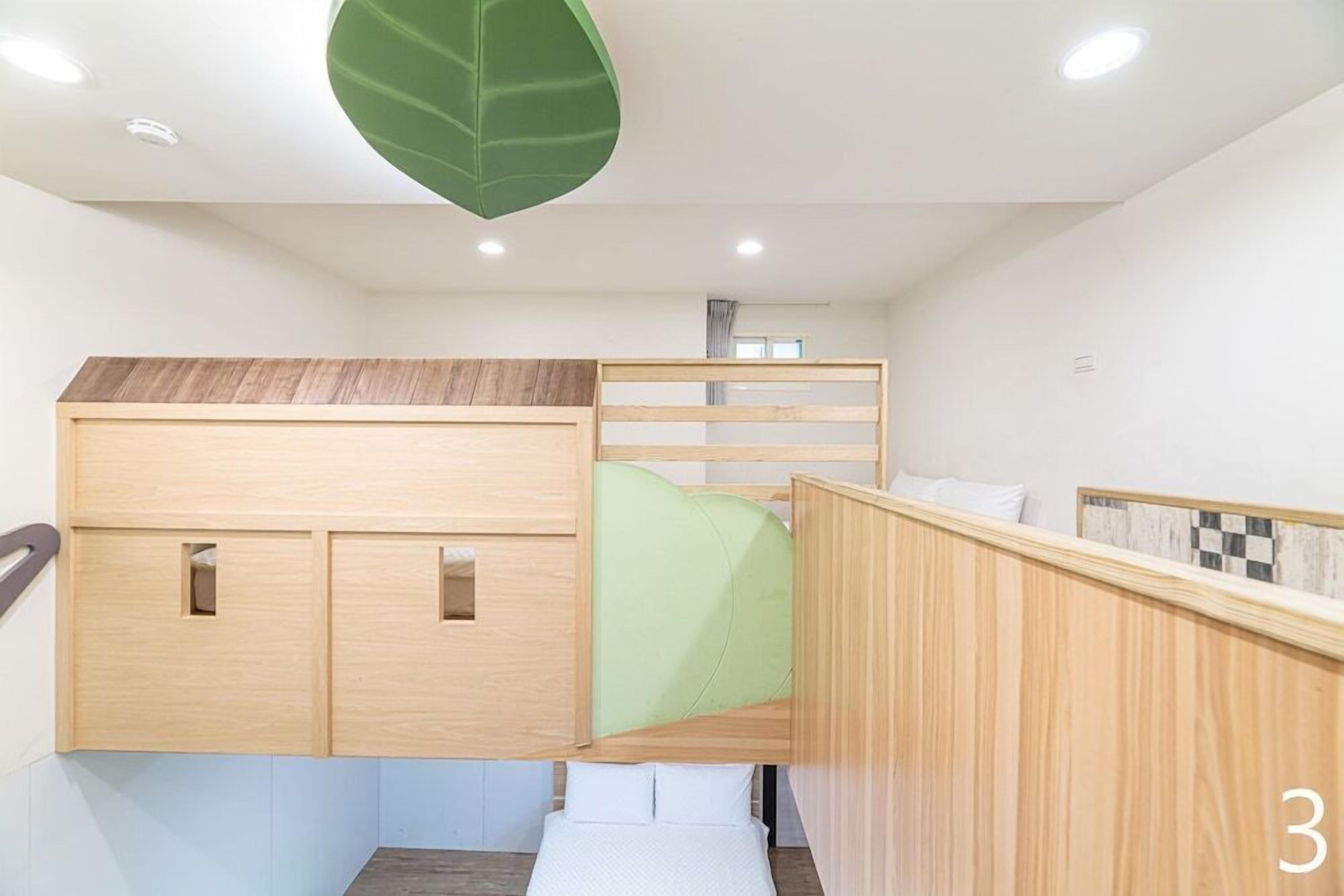Habitación compacta con una litera, un escritorio pequeño y un adorno en forma de hoja verde en el techo.