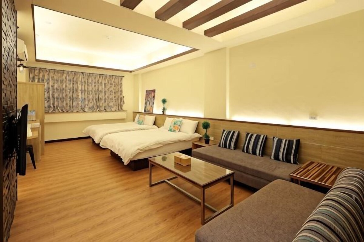 A room with a skylight, two beds, a sofa, a coffee table, and a TV.