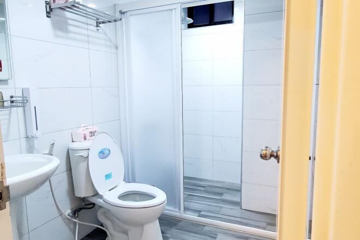 A bathroom with a toilet, sink, and shower enclosure.