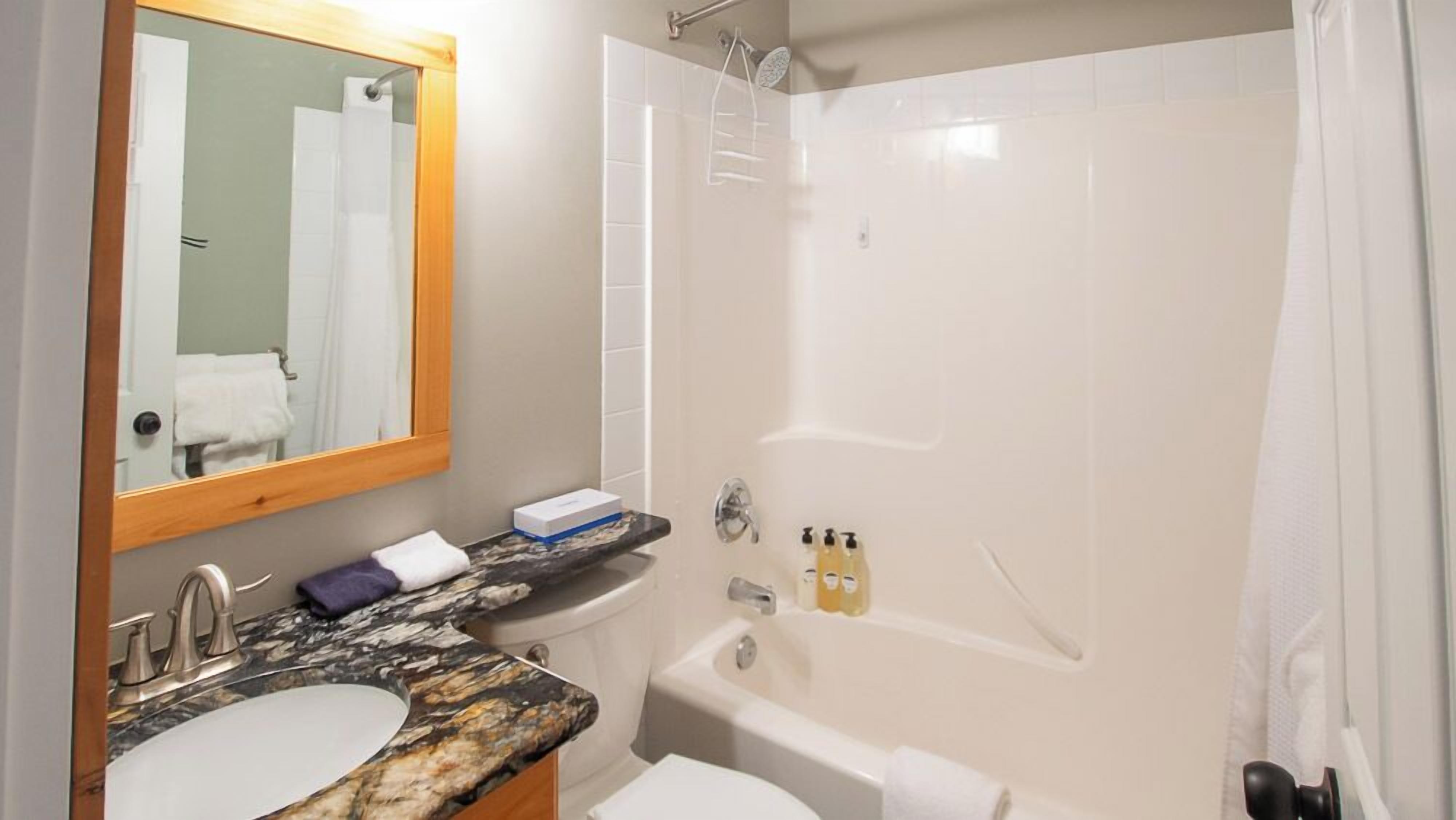 A bathroom with a marble sink, a bathtub, a shower, and a mirror.