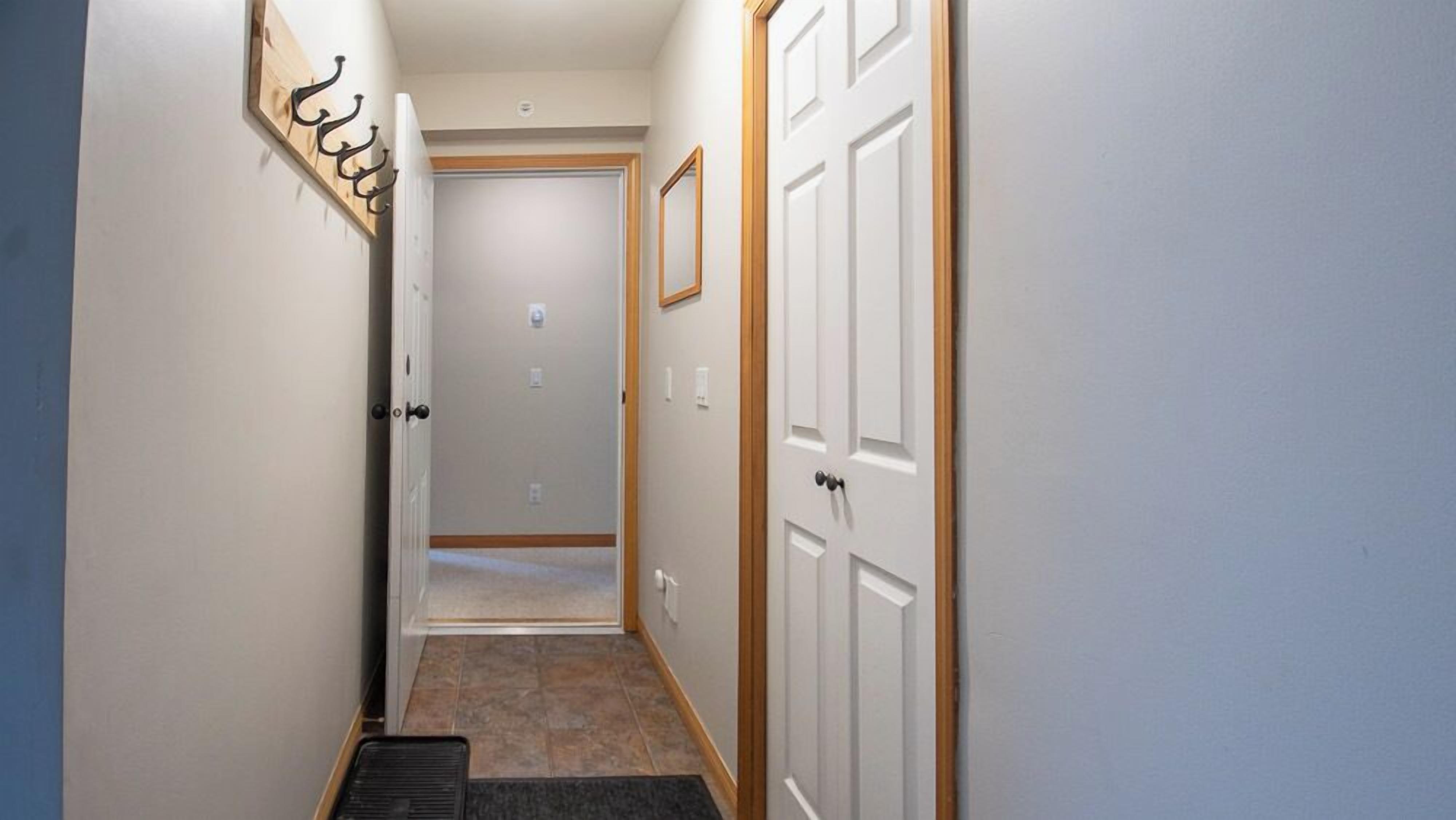 A narrow hallway with white walls, a wooden door frame, and a door with a black handle.