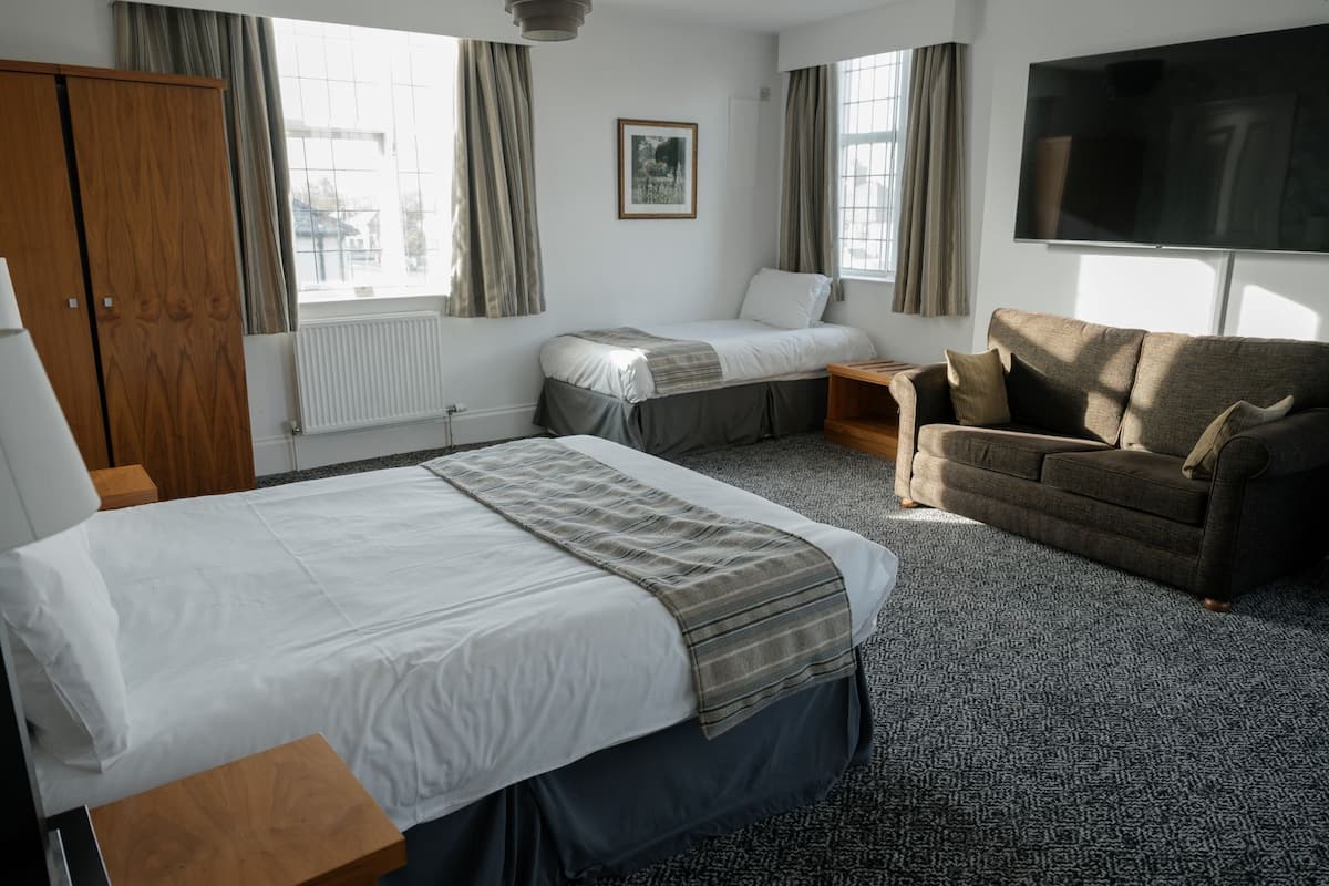Une chambre d’hôtel avec un grand lit, un canapé, une télévision et une fenêtre avec des rideaux.