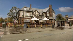Un pub traditionnel avec une enseigne indiquant « Fairway Inn » et des tables à l’extérieur, protégées par des parasols.