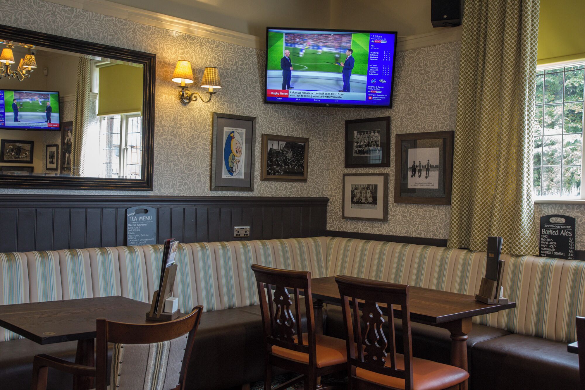 A restaurant with a TV displaying sports, framed pictures on the wall, and a menu board.