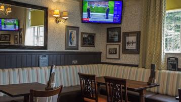 A restaurant with a TV displaying sports, framed pictures on the wall, and a menu board.