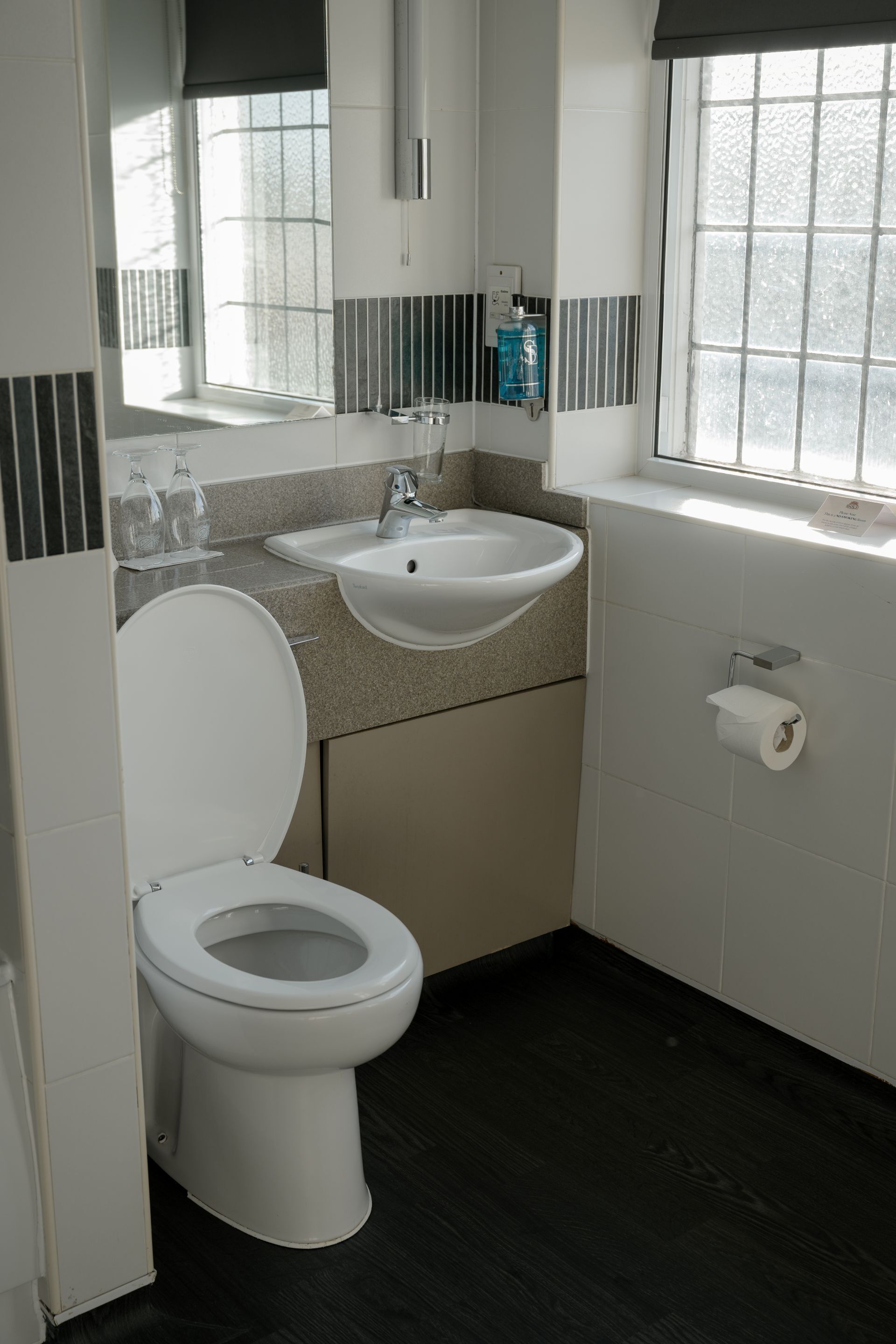 A modern bathroom with a toilet, sink, and window.