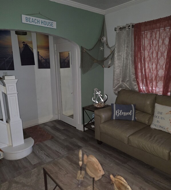 A living room with a couch, a coffee table, and a sign reading "BEACH HOUSE".