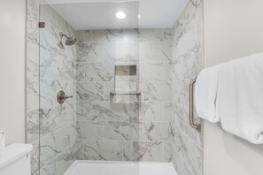 A modern bathroom with marble tiles, a shower, a toilet, and a towel rack. - 🏝️ Bay Views | Walk to Beach☀️Tristan Towers unit 8C (Pensacola Beach)