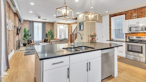 A modern kitchen with a central island, stainless steel appliances, and pendant lighting. - Brikctoria 1102 3 Bedroom Home (Kansas City)
