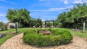 A paved garden area with a central rock feature, surrounded by well-maintained hedges and trees. - Brikctoria 1102 3 Bedroom Home (Kansas City)