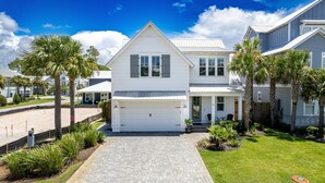 A two-story house with a white exterior, a garage, and a paved driveway leading to the entrance. - Seaside Serenity 5 Bedroom Home (Miramar Beach)