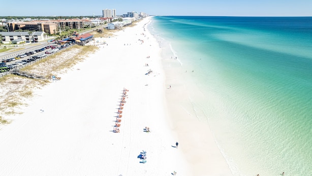 An aerial view of a beach with a row of beach umbrellas, a sandy shore, and a clear blue ocean. - Seaside Serenity 5 Bedroom Home (Miramar Beach)