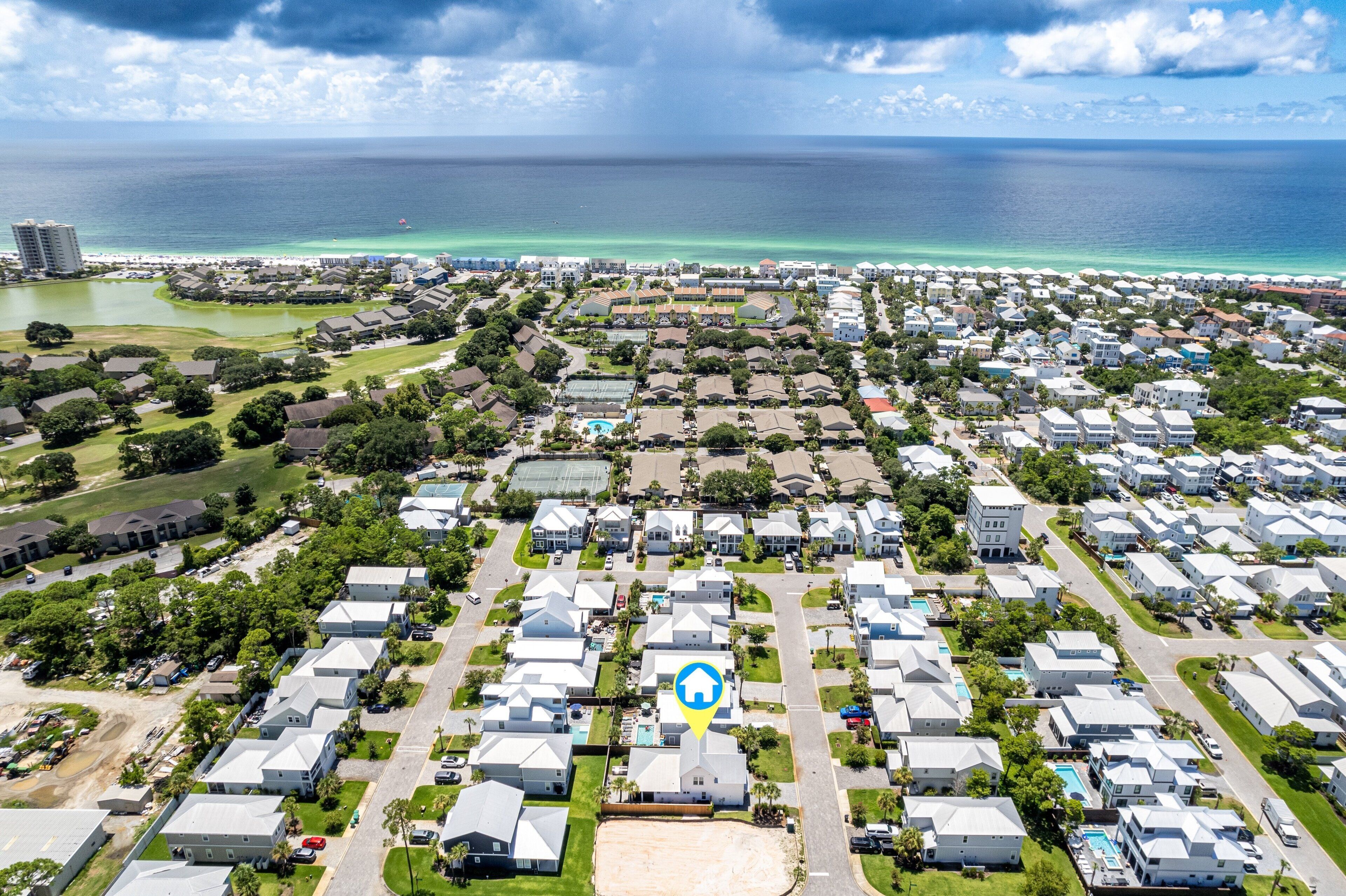 A residential area with houses, a golf course, and a view of the ocean.