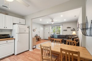 A modern kitchen with white cabinets, a refrigerator, and a microwave. There is a dining area with a wooden table and chairs. - 2BR Cape May Retreat - Yard, Beach & Parking (Cape May)