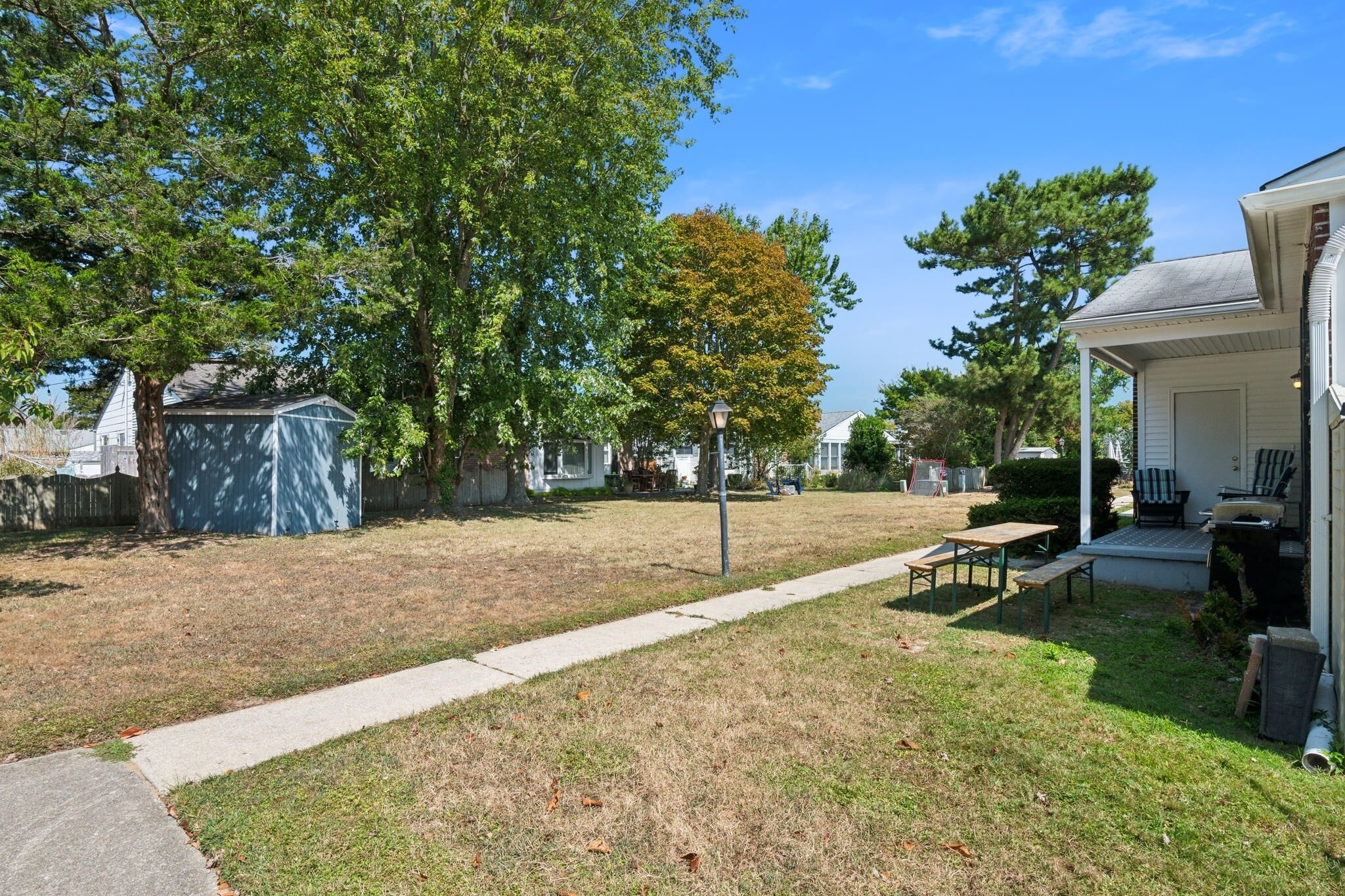 A residential backyard with a covered play area, a picnic table, and a covered porch.