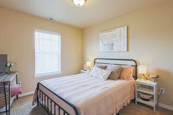 A bedroom with a bed, bedside tables, a lamp, a window, and a painting on the wall. - Cozy Corner Oasis With Hot Tub 4 Bedroom Home (Twin Falls)